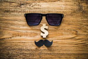 A face made out of sunglasses, a brown dollar sign for the nose, and a little black mustache where the mouth would be - all of this is against a wood grain background.