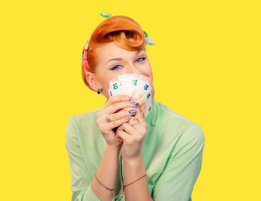Retro image of red-headed young woman in green shirt against a yellow background holding money close to her nose.
