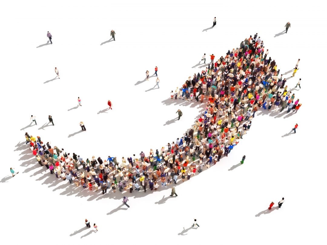 A crowd of people against a white background form a swooping arrow.