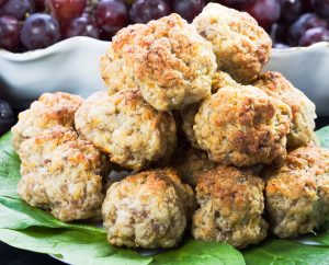 For recipe request. Sausage balls on a plate with greens of spinach and grapes.