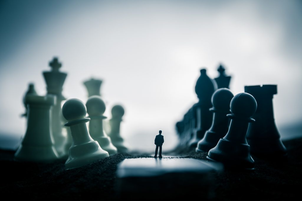 Chess concept of business and strategy ideas. Silhouette of a man standing in the middle of the road with giant chess figures.