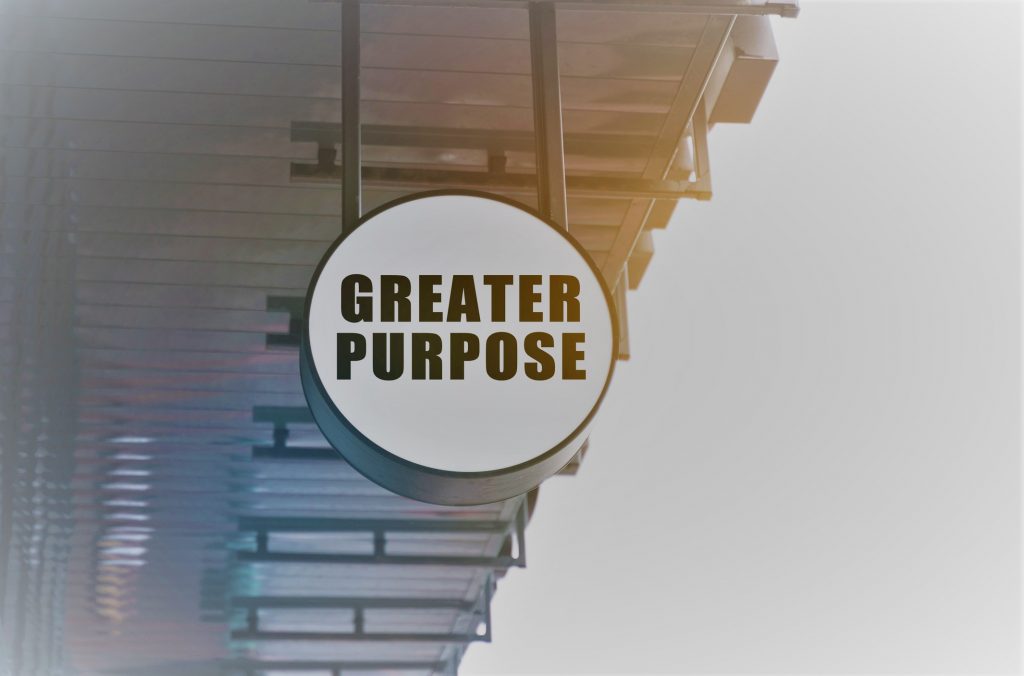 There is a circular sign under the roof of the train station that says - Greater Purpose