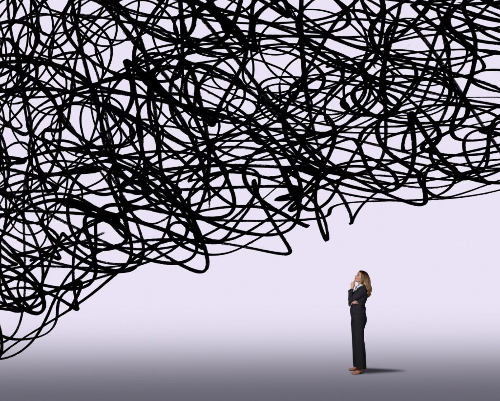 Woman in a business suit stands below a large cloud of black scribbles.