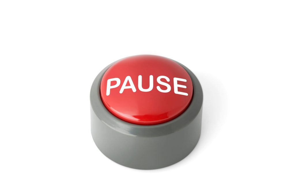 Red circular push button labeled 'Pause' isolated on white background