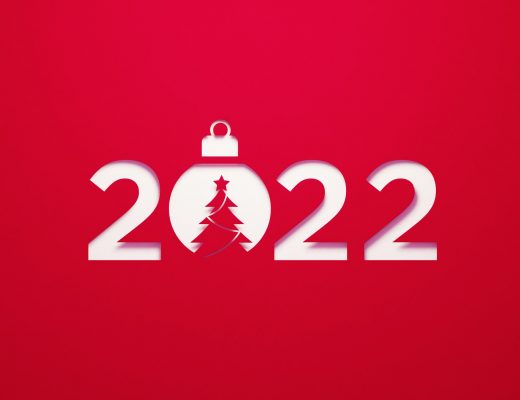 2022 sitting next to a Christmas bauble on red background. Horizontal composition with copy space. 2022 new year concept.